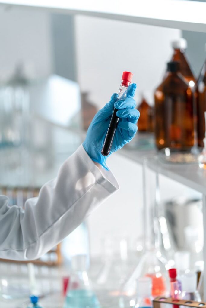 Close-up of a hand holding a test tube in a laboratory setting, symbolizing scientific research.