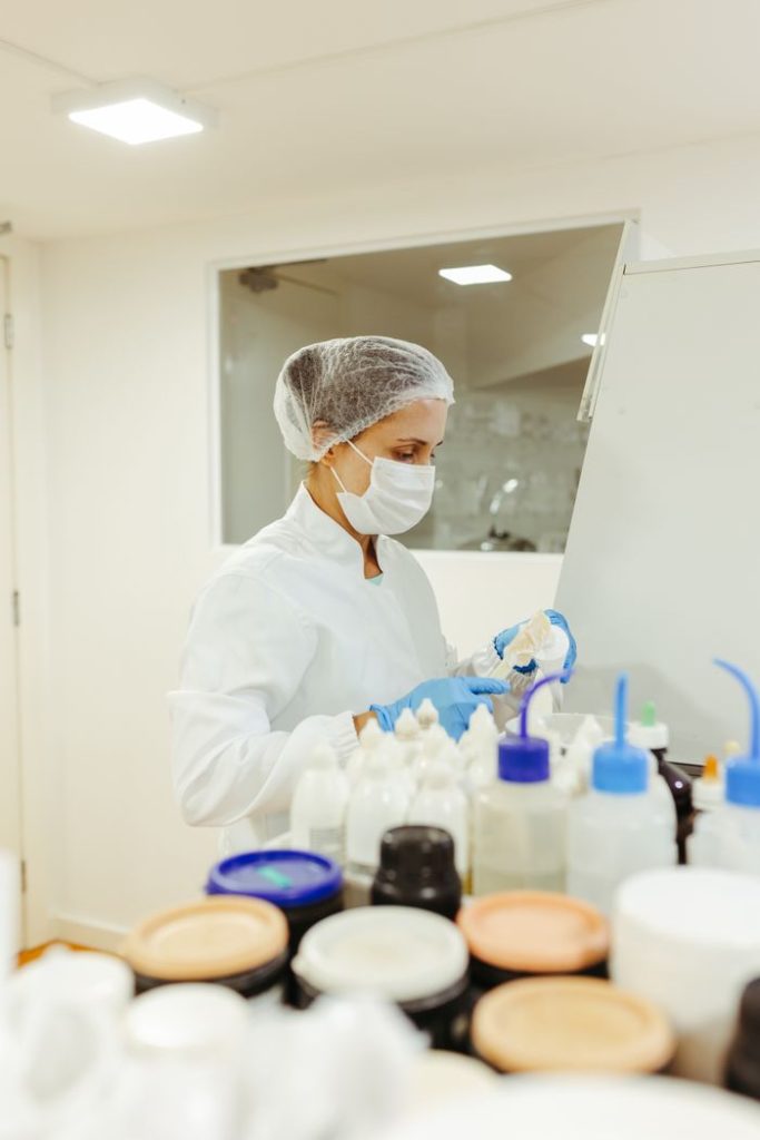 Scientist in lab coat and protective gear conducting an experiment in a laboratory setting.